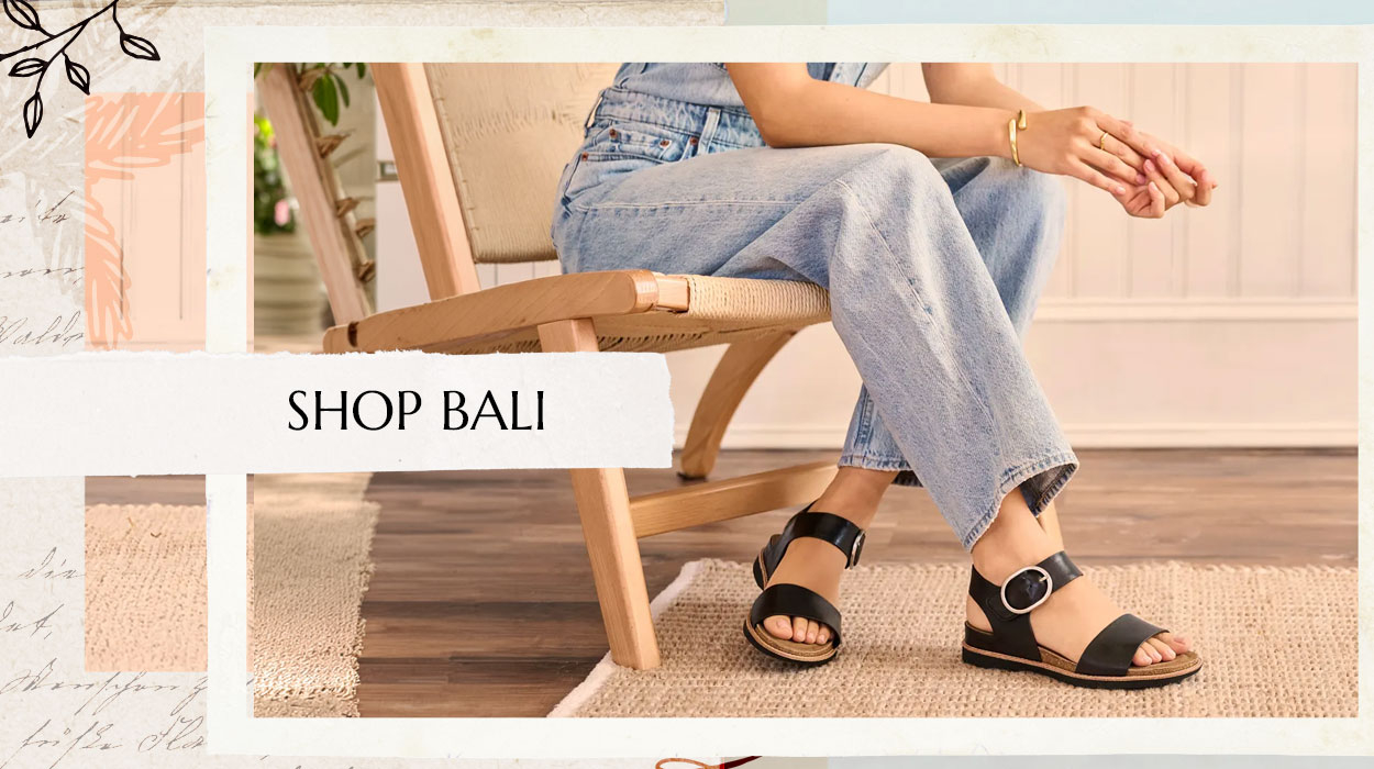 Woman sitting on a chair wearing blue jeans and the Bali sandal in black. Shop the Bali.