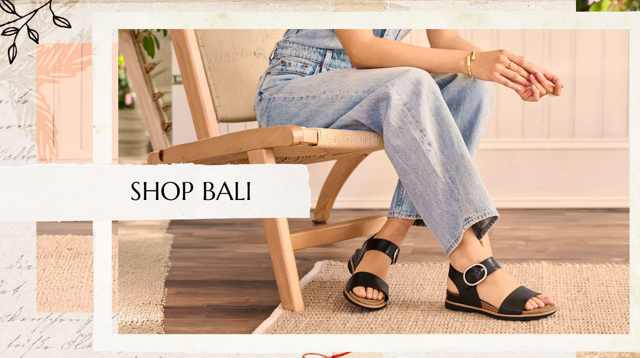 Woman sitting on a chair wearing blue jeans and the Bali sandal in black. Shop the Bali.